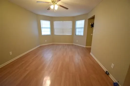 a view of an empty room with wooden floor and a window