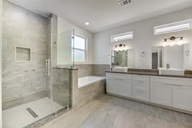 a bathroom with a bathtub a double vanity sink and mirror