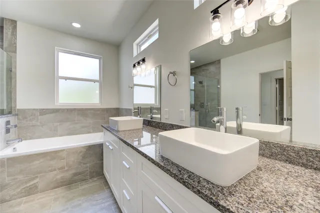 a spacious bathroom with a tub double sink and a mirror