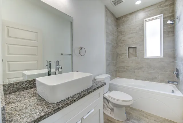 a bathroom with a granite countertop sink mirror toilet and bathtub