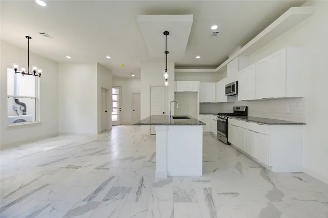 a large kitchen with kitchen island a sink a center island stainless steel appliances and a fireplace