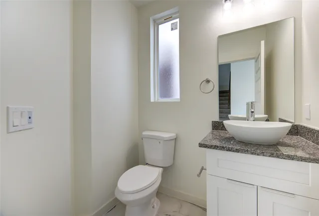 a bathroom with a granite countertop toilet a sink and mirror