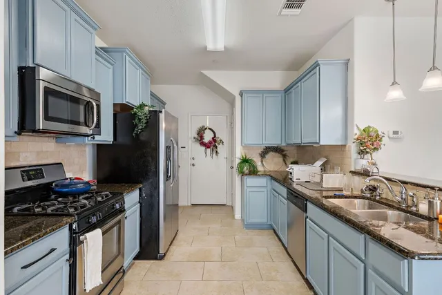 a kitchen with stainless steel appliances granite countertop a sink stove and refrigerator