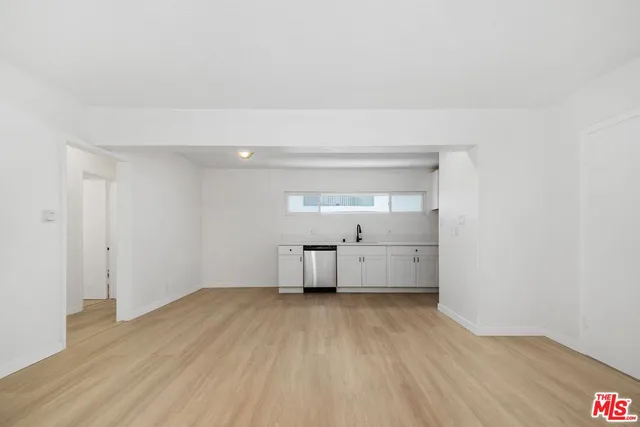 a large kitchen with a sink dishwasher a stove and white cabinets with wooden floor