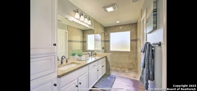 a spacious bathroom with a double vanity sink a large mirror a shower and a bathtub