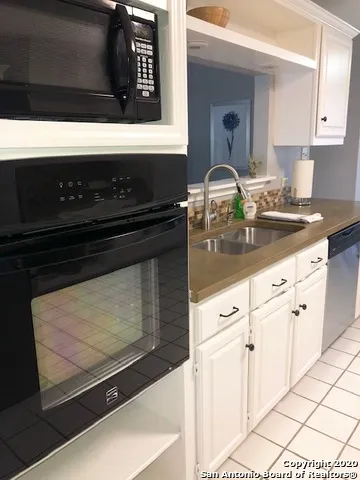 a kitchen with granite countertop white cabinets and black appliances