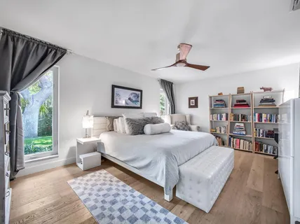 a bedroom with a bed a large window and book shelf