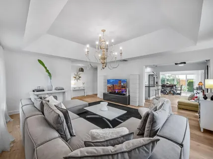 a living room with furniture a chandelier and a flat screen tv