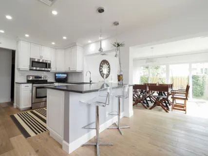 a kitchen with stainless steel appliances granite countertop a stove top oven a sink a dining table and chairs with wooden floor