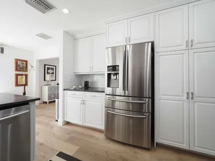 a kitchen with stainless steel appliances white cabinets and a refrigerator