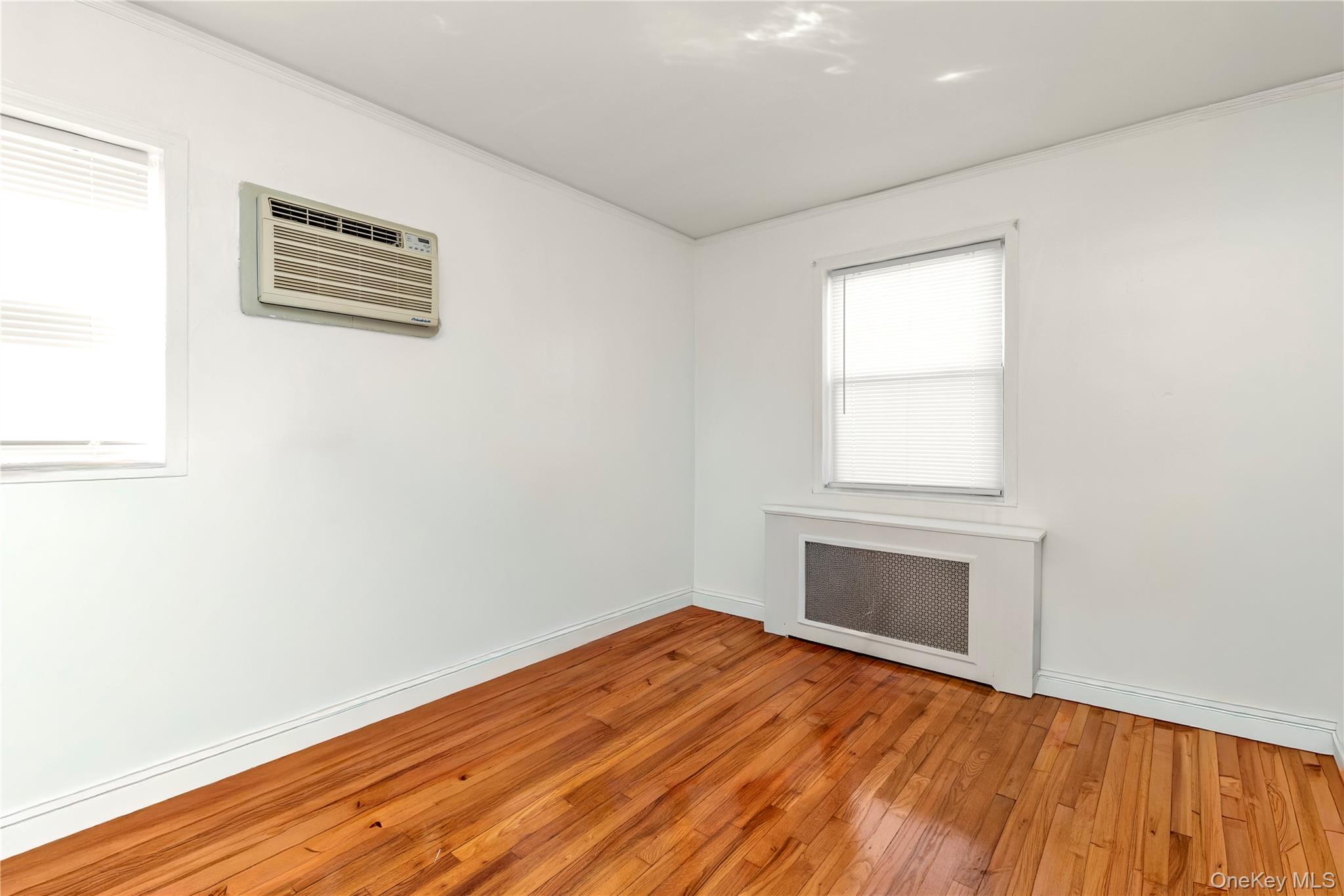 82-31 165th Street Queens, NY 11432 - Photo 9 of 16 an empty room with wooden floor and windows