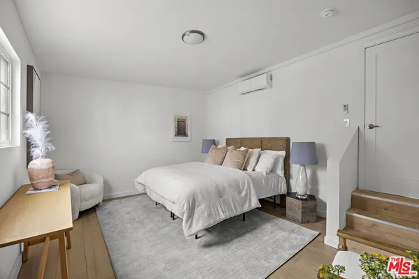 a spacious bedroom with a bed and wooden floor