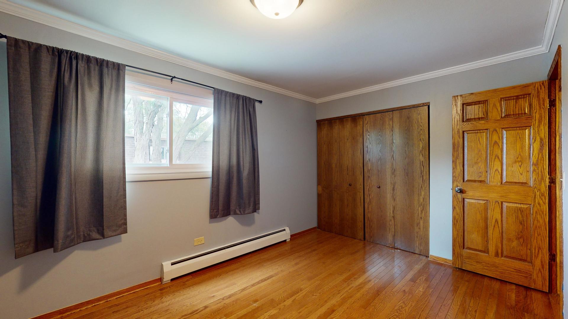 2302 West Algonquin Road, Unit 12 Rolling Meadows, IL 60008 - Photo 12 of 22 an empty room with wooden floor and windows