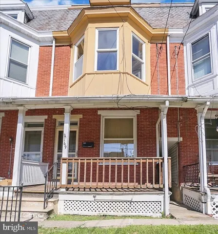 a view of a brick house with large windows and a yard
