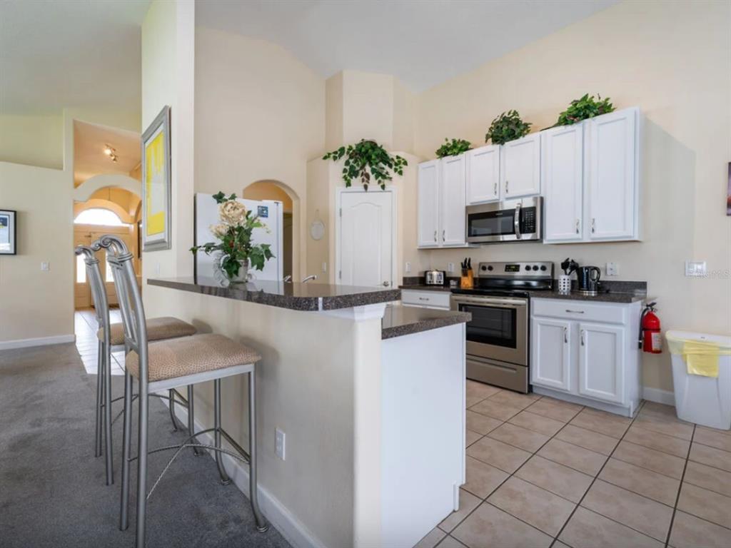 641 Old Bridge Circle Davenport, FL 33897 - Photo 11 of 28 a kitchen with granite countertop a stove a sink and a microwave