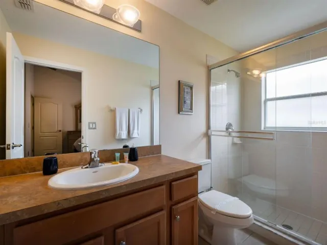 a bathroom with a granite countertop sink toilet a mirror and shower