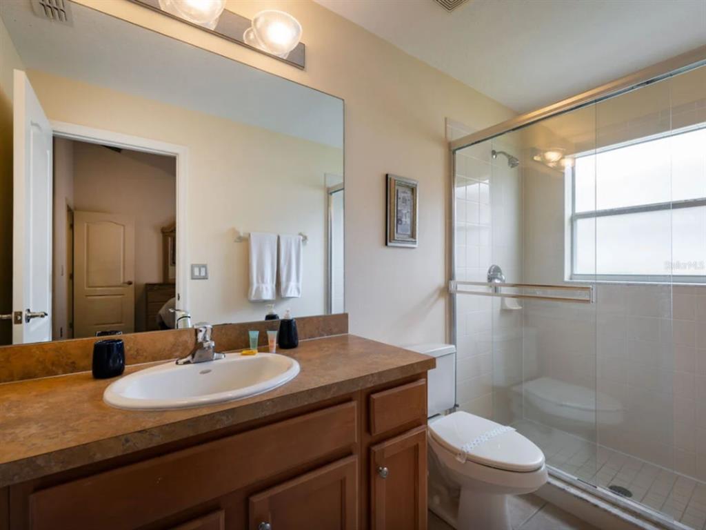 641 Old Bridge Circle Davenport, FL 33897 - Photo 21 of 28 a bathroom with a granite countertop sink toilet a mirror and shower