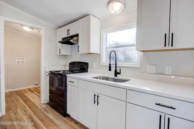 a kitchen with a sink and a stove top oven with wooden floor