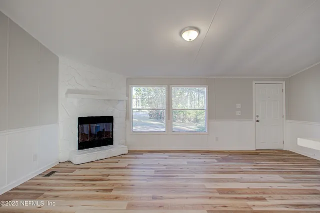 a view of empty room with wooden floor and fireplace