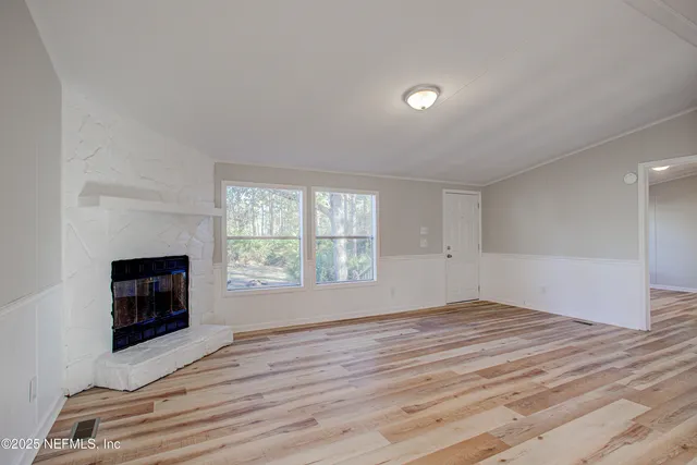 a view of empty room with wooden floor and fireplace