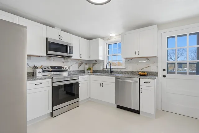 a kitchen with white cabinets stainless steel appliances and a counter space
