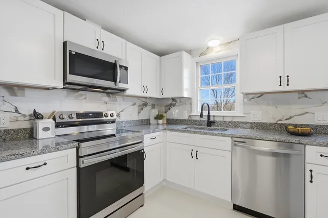 a kitchen with stainless steel appliances granite countertop white cabinets a sink and a stove