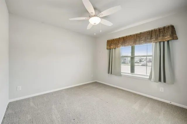 an empty room with a window and a ceiling fan