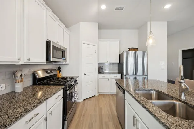 a kitchen with kitchen island granite countertop a sink a stove and refrigerator