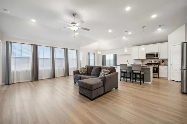 a living room with furniture and kitchen view with wooden floor