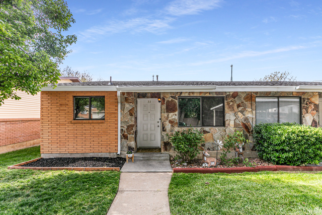 947 Canyon Road, Unit 33 Ogden, UT 84404 - Photo 1 of 19 Exterior featuring a stone veneer facade, brick accent wall, white entry door, multiple windows, and a concrete walkway