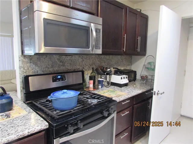 a kitchen with granite countertop stainless steel appliances stove top oven and cabinets