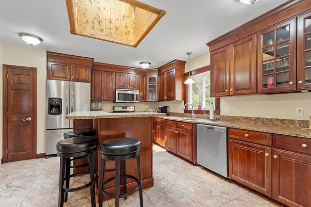 a kitchen with stainless steel appliances granite countertop wooden cabinets a refrigerator and a sink