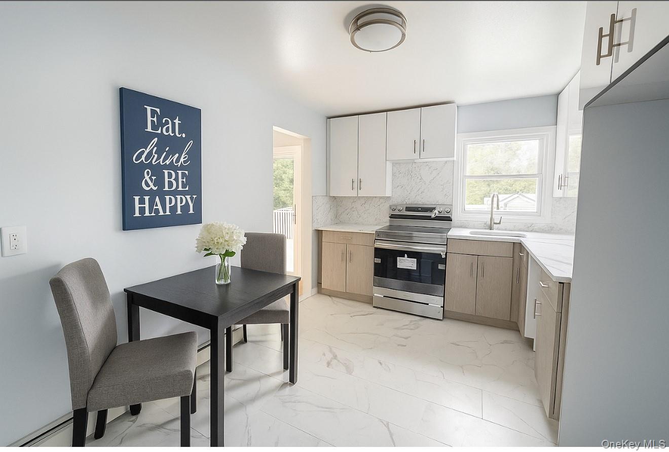 324 Buckingham Road Cedarhurst, NY 11516 - Photo 2 of 12 Kitchen featuring light marble finish flooring, electric stove, backsplash, a baseboard radiator, and white cabinetry