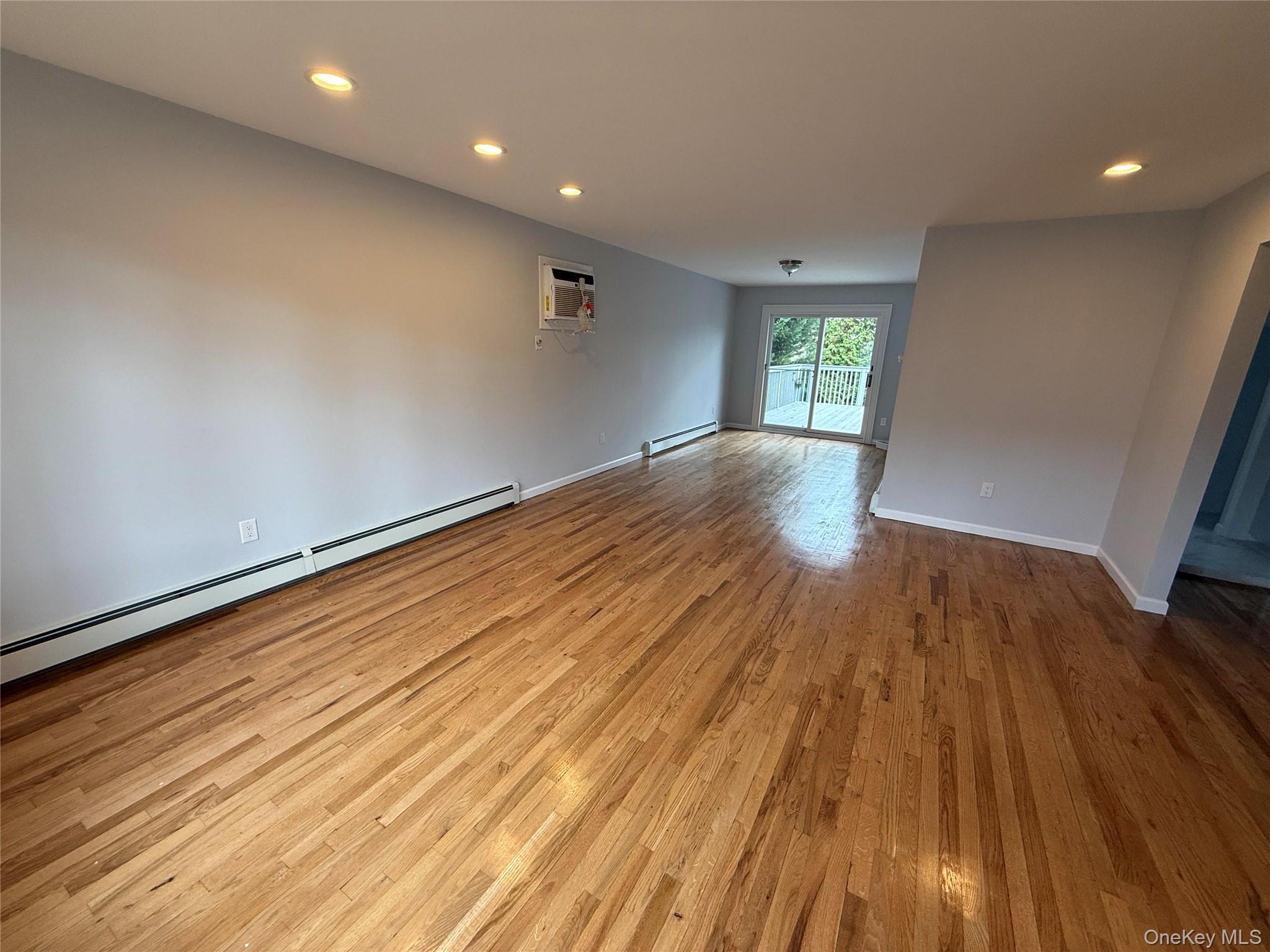324 Buckingham Road Cedarhurst, NY 11516 - Photo 3 of 12 Empty room with baseboard heating, recessed lighting, light wood-style flooring, and a wall mounted AC