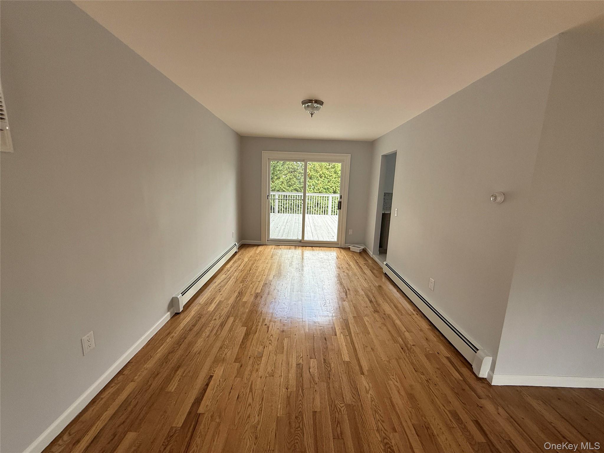 324 Buckingham Road Cedarhurst, NY 11516 - Photo 5 of 12 Spare room featuring a baseboard radiator and light wood-style floors