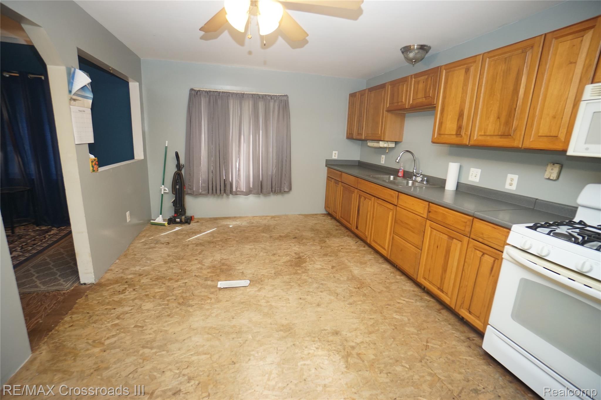 7150 Sheldon Road Belleville, MI 48111 - Photo 8 of 11 Kitchen featuring wood cabinetry, a stainless steel sink, and a white gas range