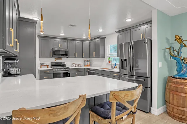 a kitchen with stainless steel appliances a refrigerator a stove a sink cabinets and a dining table