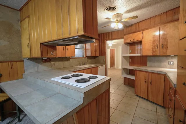 a kitchen with kitchen island a chandelier and wooden cabinets