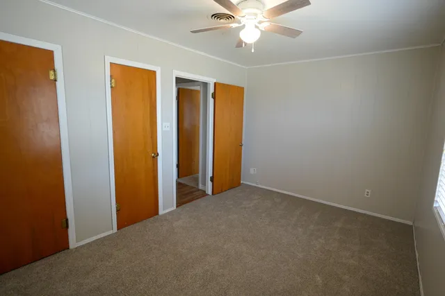 an empty room with closet and a ceiling fan