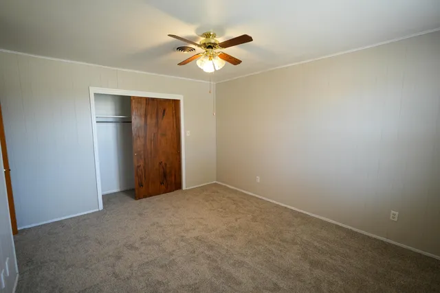 an empty room with a chandelier fan and a window
