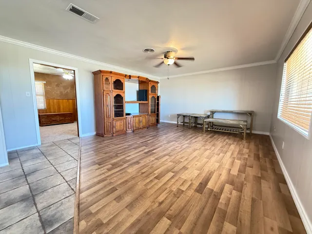 an empty room with wooden floor fan and windows