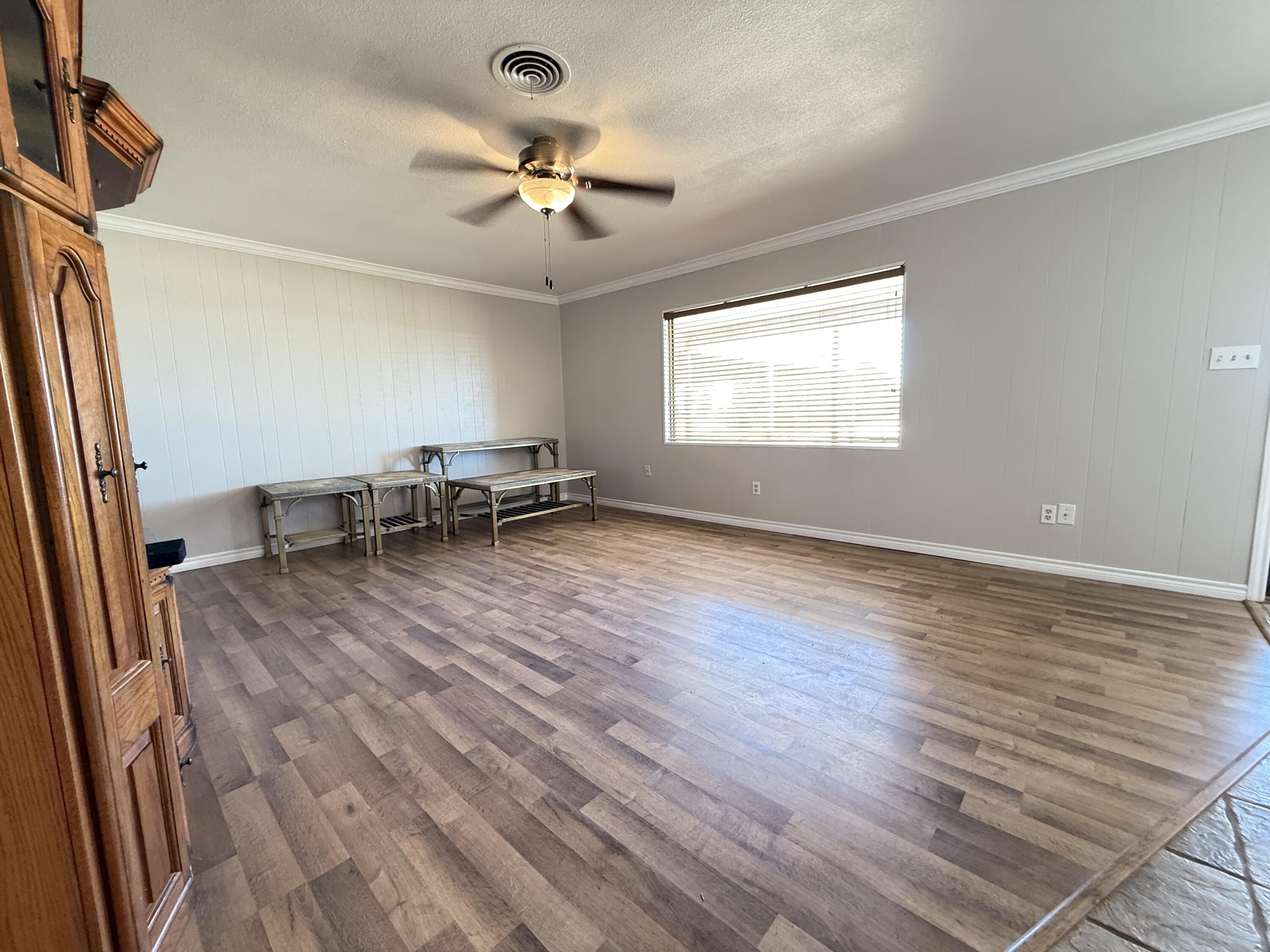 3391 Fisher Road Levelland, TX 79336 - Photo 4 of 47 an empty room with wooden floor fan and windows