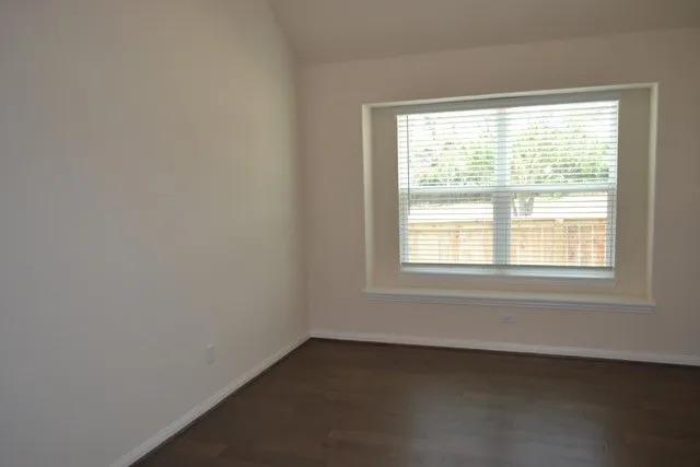 a view of an empty room with closet and wooden floor