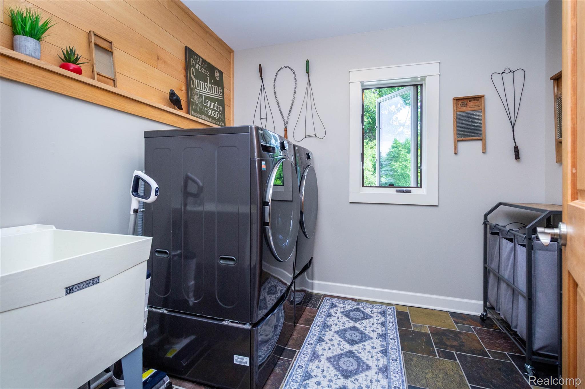 9887 Hadley Road Clarkston, MI 48348 - Photo 27 of 56 Laundry room featuring slate-tile flooring, a wood-paneled accent wall with shelving, and light gray painted walls