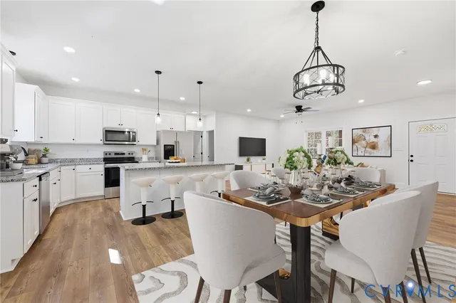 a view of a dining room and livingroom with furniture wooden floor a chandelier