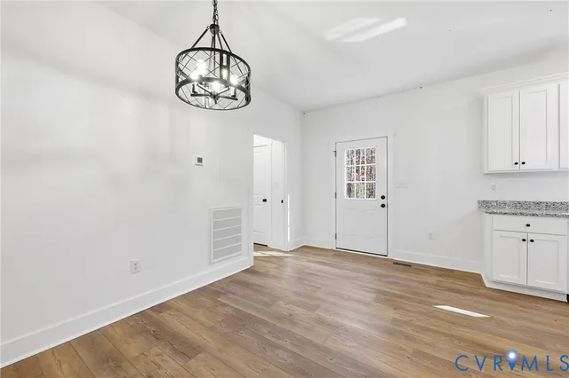 a view of an empty room with window and wooden floor