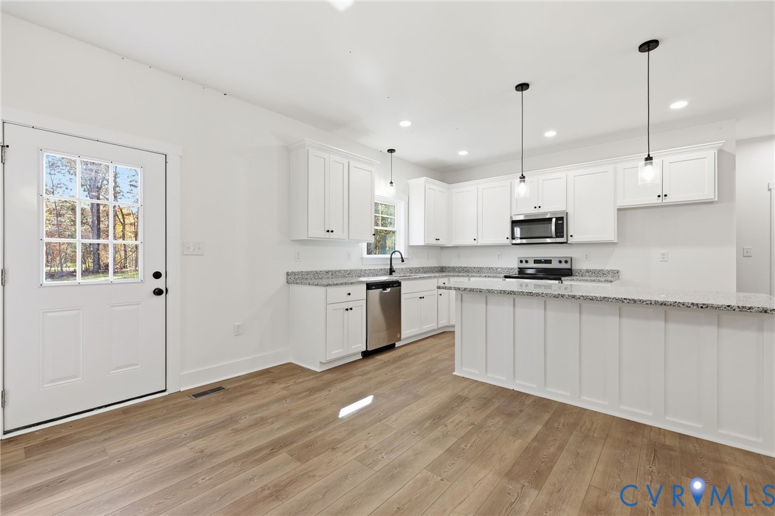 5888 Cartersville Road New Canton, VA 23123 - Photo 9 of 33 a kitchen with stainless steel appliances kitchen island granite countertop a stove a sink and white cabinets with wooden floor