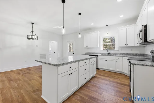 a kitchen with kitchen island white cabinets appliances and a wooden floor