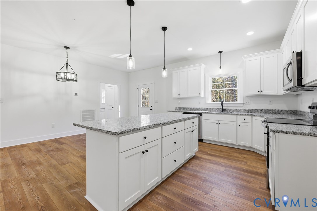 5888 Cartersville Road New Canton, VA 23123 - Photo 10 of 33 a kitchen with kitchen island white cabinets appliances and a wooden floor