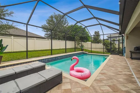 a view of swimming pool with chairs and backyard